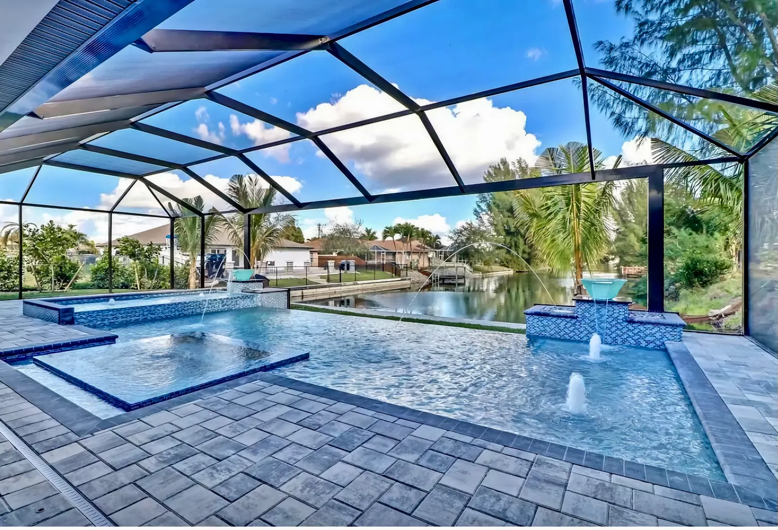 A screened lanai pool with waterfall spouts and a spa, on a bright Florida afternoon